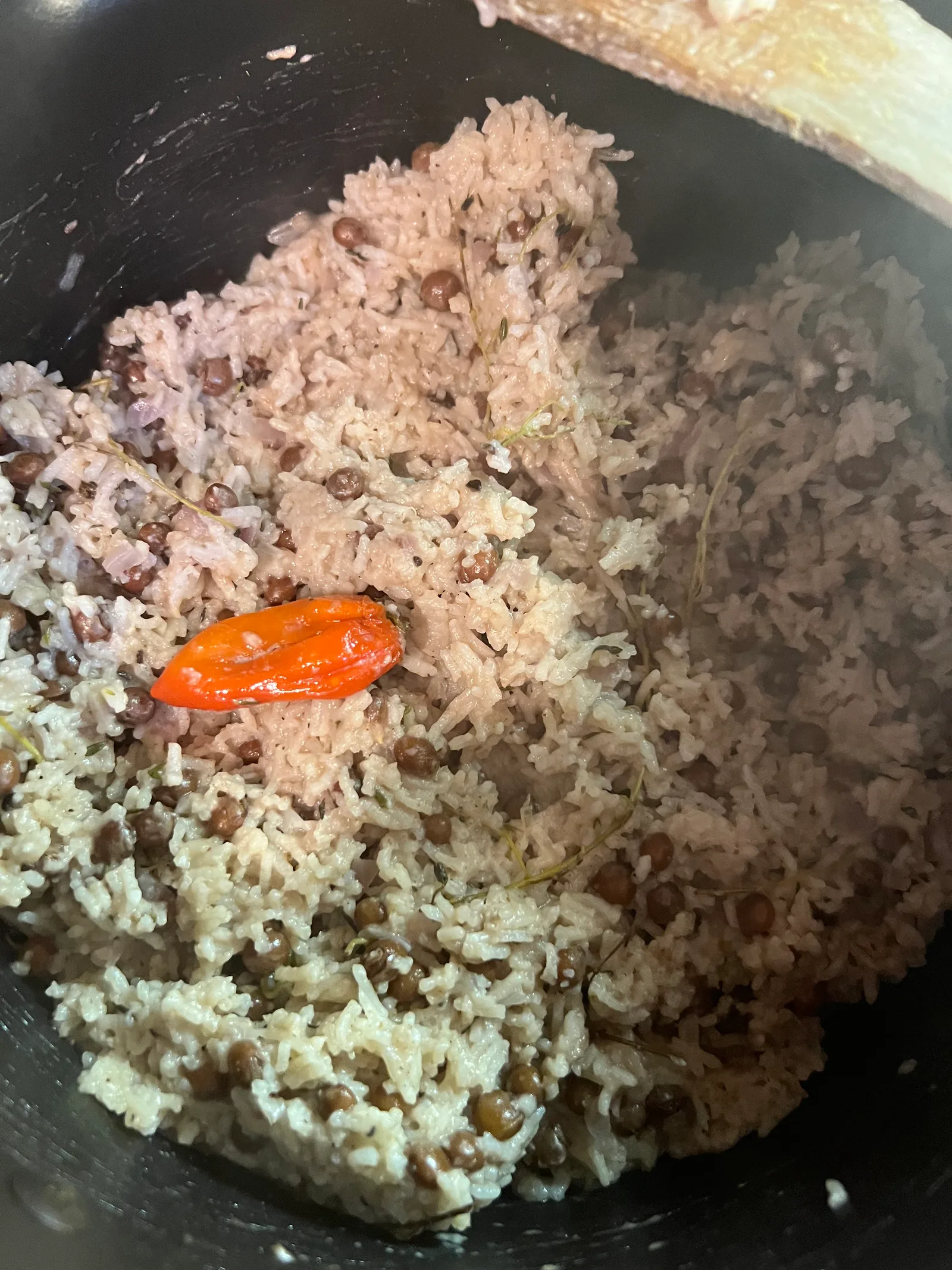 Rice and peas in the pot with a scotch bonnet on top.