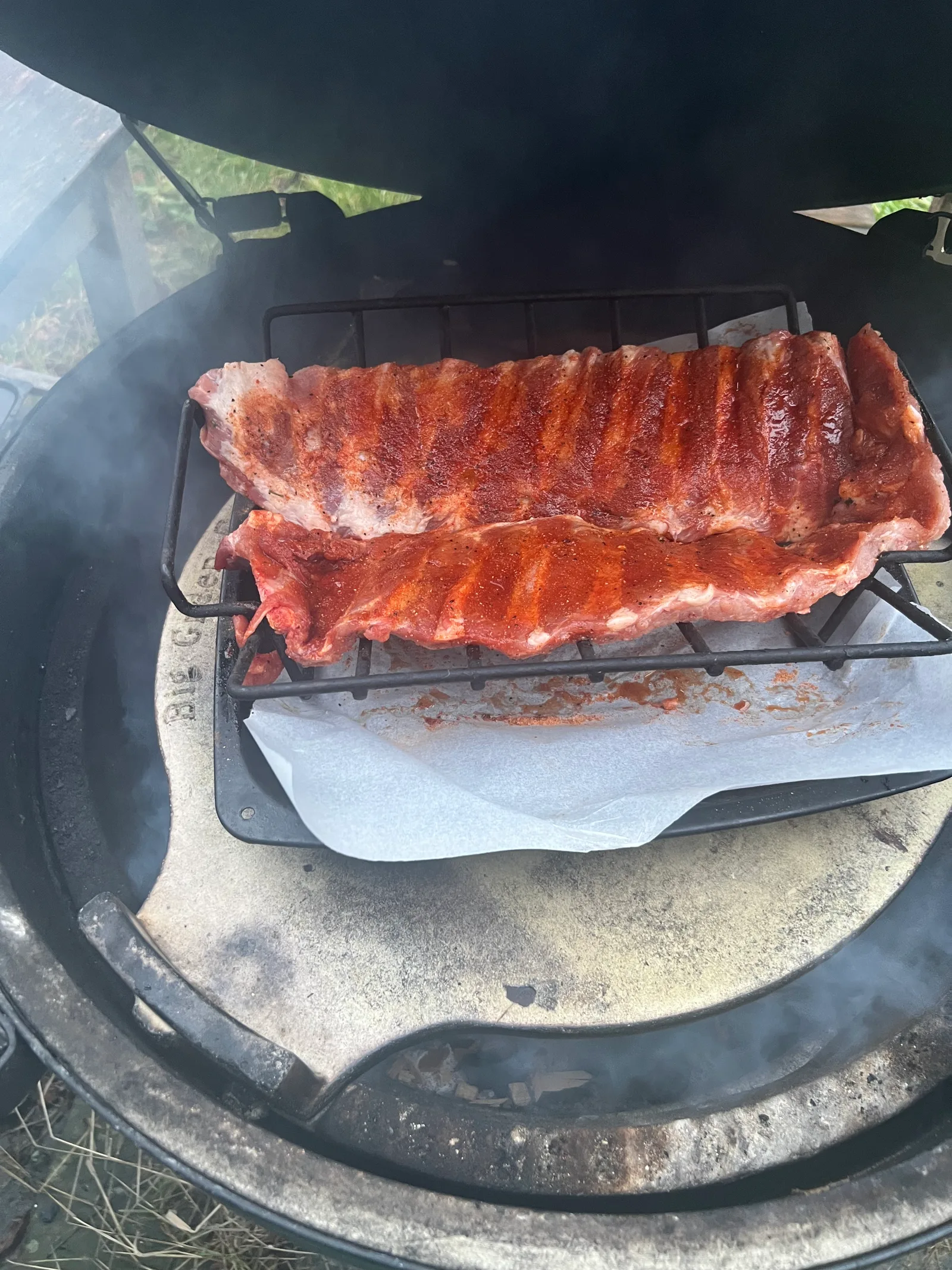 Raw racks of ribs on the Big Green Egg, smoke going.