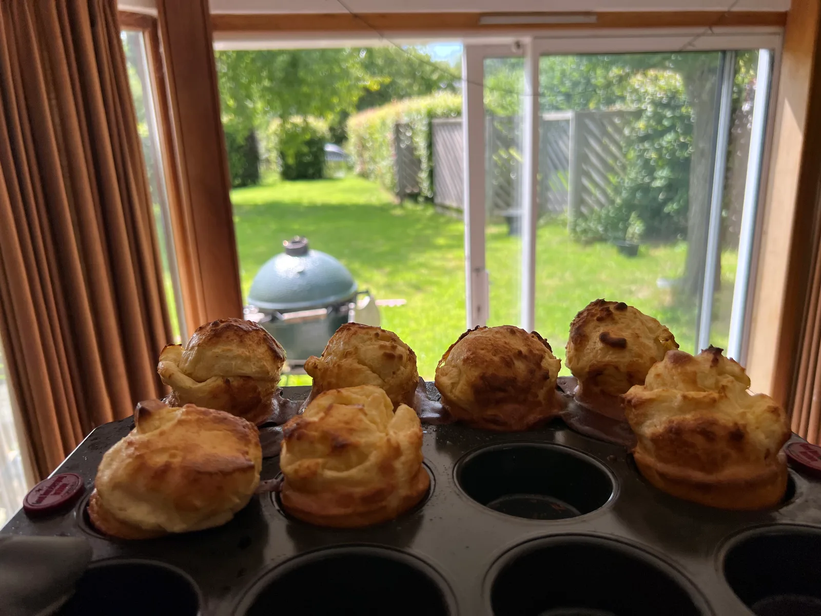 Yorkshire puddings in the tin, the Big Green Egg visible through the window.