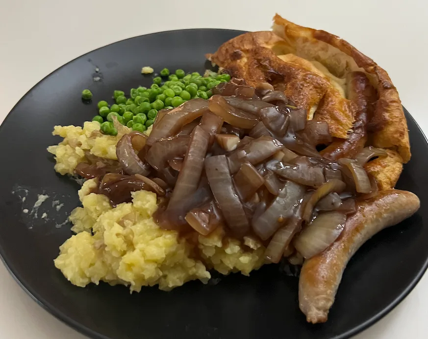 Toad in the hole with mash, peas and onion gravy.