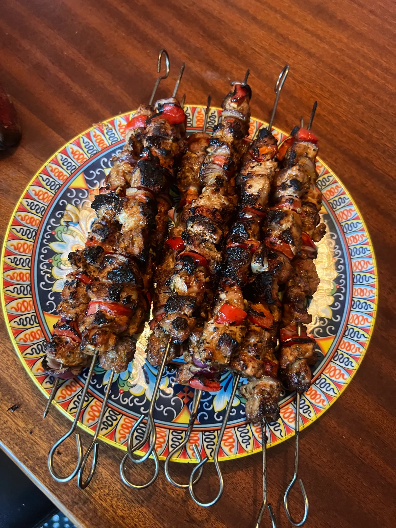 Souvlaki stacked on a colourful patterned plate.